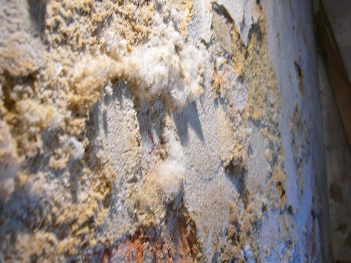 A concrete surface with yellow-ish white crystal deposits sprouting out from it